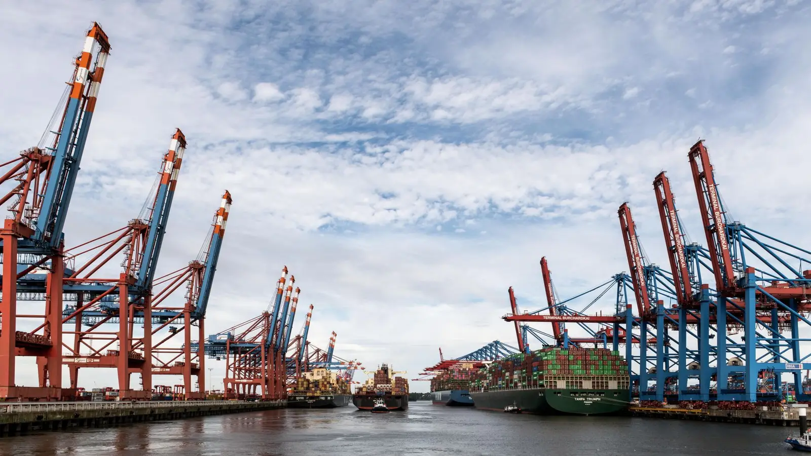 Container cranes on a port dock under a cloudy sky